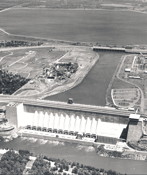 Black-and-white aerial photograph of the newly completed Sir Adam Beck No. 2 generating station beside the Niagara River in the mid-1950s, with the forebay canal and reservoir lands stretching behind it.